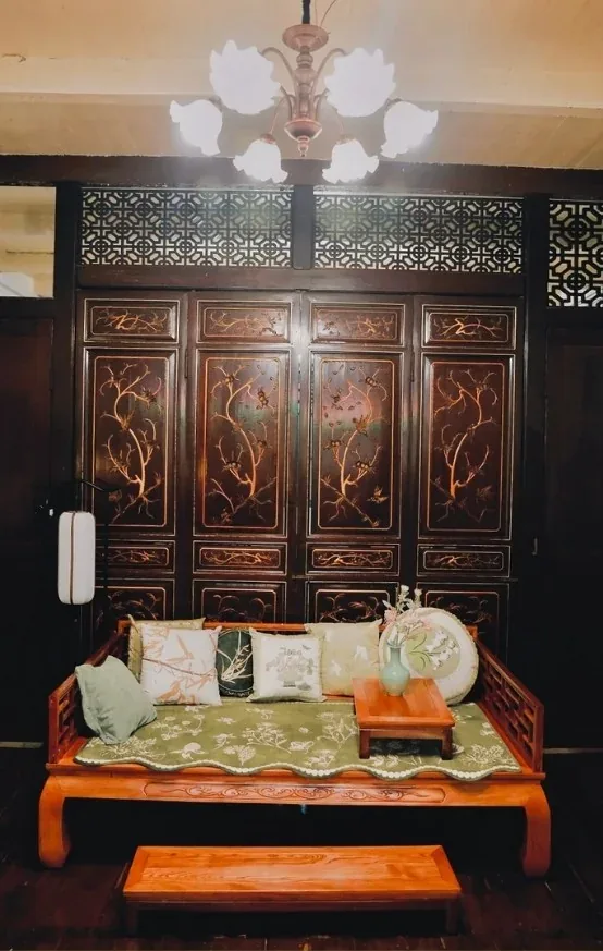马六甲店内的雕花木榻，背后是描金花鸟屏风与格栅窗